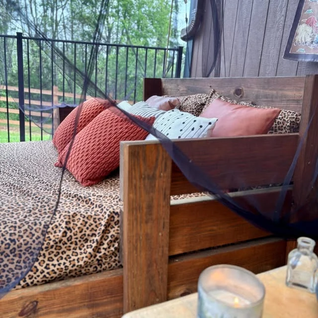 The wooden daybed swing with cushions in the rustic pavilion